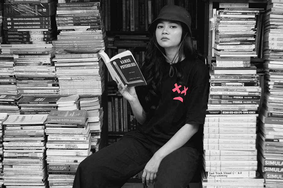 Woman in Black Crew Neck T-shirt Sitting on Books